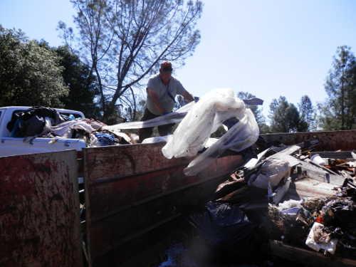 Citizens Caring for Clearlake volunteer Robert Hitchcock unloads a truck bed full of trash collected in the area east of Pomo Elementary School in Clearlake, Calif., as part of a weeklong effort to clean the area. Volunteers are separating recyclable items as they continue the cleanup effort, which will conclude on Friday, July 20, 2015. Photo by Denise Rockenstein/Lake County News. 071515cc4ccleanupguy
