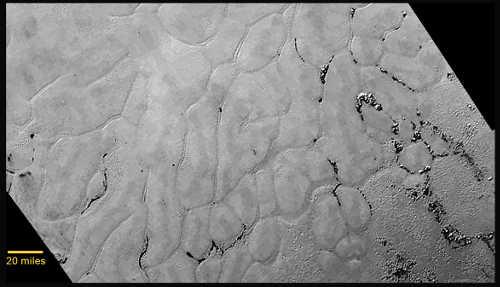 In the center left of Pluto’s vast heart-shaped feature – informally named “Tombaugh Regio” – lies a vast, craterless plain that appears to be no more than 100 million years old, and is possibly still being shaped by geologic processes. This frozen region is north of Pluto’s icy mountains and has been informally named Sputnik Planum (Sputnik Plain), after Earth’s first artificial satellite. The surface appears to be divided into irregularly-shaped segments that are ringed by narrow troughs. Features that appear to be groups of mounds and fields of small pits are also visible. This image was acquired by the Long Range Reconnaissance Imager (LORRI) on July 14 from a distance of 48,000 miles (77,000 kilometers). Features as small as one-half mile (1 kilometer) across are visible. The blocky appearance of some features is due to compression of the image. Credits: NASA/JHUAPL/SWRI. 071715plutosheart
