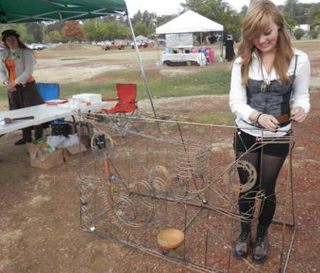 Natalya Dickson checks out an “Awe-Mazing Maze” Saturday, October 25, 2014, during “Spirits on the Loch” at Austin Park in Clearlake, Calif. The event continues 10 a.m. to 6 p.m. today. Also pictured is marble maze proprietor Jackie Gaulden (left), whose husband Matt crafts the metal maze sculptures. Photo by Denise Rockenstein/Lake County News. 102514spiritsnatalya