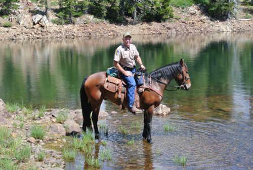 Modoc cooling his feet off in a back country lake with California Department of Fish and Wildlife Officer Jerry Karnow aboard. Photo courtesy of the California Department of Fish and Wildlife. equinepartners2