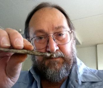 Renne examines a sample of hardened volcanic ash, called tuff, from the main extinction level where impact debris is found. Photo by Paul Renne. dinosaurrenneash