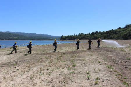 Members of the Willits Organized Crew start laying a hose line along Lake Mendocino near Ukiah, Calif., on Thursday, April 17, 2014, with first-year crewmember Bryan Stencil in the lead. Photo courtesy of the Mendocino National Forest. 041714willitscrew1