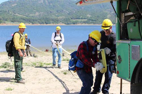 Willits Organized Crewmember Bryan Stencil rewinds fire hose on the back of Forest Service Engine 42 with the assistance of fellow crewmember Nolan Lawson. Crewmember Kenneth Marrs holds the hose taught in the background as Engine 42 crewmember Richard Bruin looks on. The training took place on Thursday, April 17, 2014, near Ukiah, Calif. Photo courtesy of the Mendocino National Forest. 041714willitscrew3