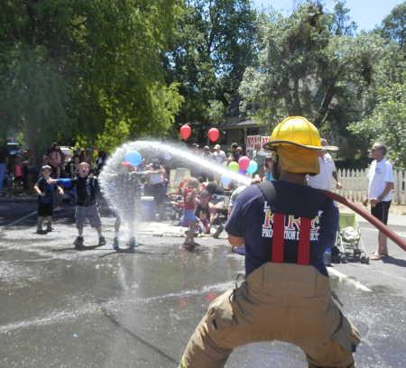 A Lake County Fire Protection firefighter helps keep fans cool during the Lower Lake Daze Parade on Sunday, May 25, 2014, in Lower Lake, Calif. Photo by Denise Rockenstein. 052514paradefirehose