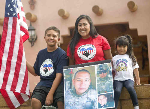 Evita De La Cruz, her 4-year-old daughter and 12-year-old son with a picture of her husband, Sgt. James De La Cruz, who died by suicide in January 2013. Courtesy photo. vetssuicidedelacruz