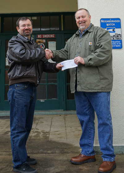 From left, Nathan Maxman, executive director of the Northshore Community Center in Lucerne, Calif., receives a $2,000 check from Darin McCosker, local area manager for Cal Water's Redwood Valley District, on Friday, December 9, 2016. Photo by Elizabeth Larson/Lake County News. 120916calwatercheck
